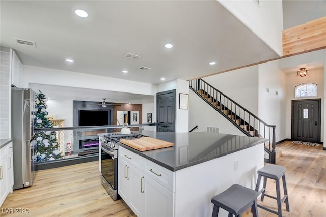 kitchen featuring a center island, light hardwood / wood-style floors, a kitchen bar, white cabinets, and appliances with stainless steel finishes