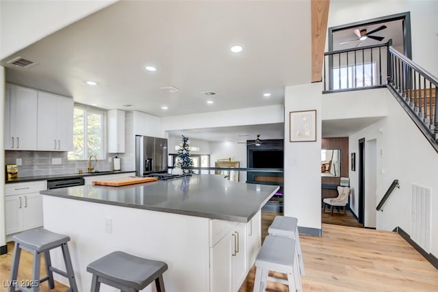 kitchen with white cabinets, a kitchen breakfast bar, sink, decorative backsplash, and stainless steel appliances