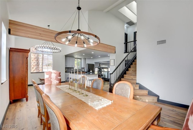 dining room with lofted ceiling with beams, light hardwood / wood-style flooring, and an inviting chandelier