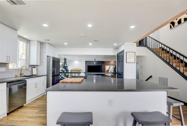 kitchen featuring a center island, sink, stainless steel appliances, a kitchen breakfast bar, and white cabinets