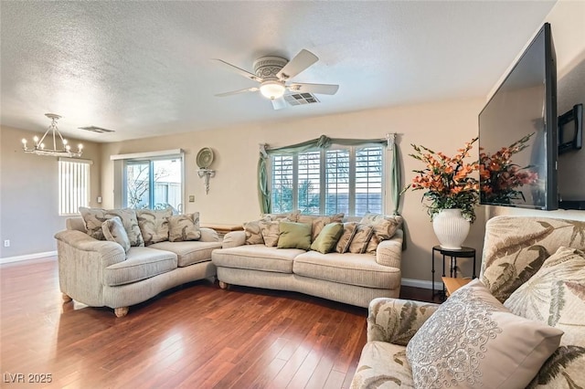 living room featuring a textured ceiling, ceiling fan with notable chandelier, and dark wood-type flooring