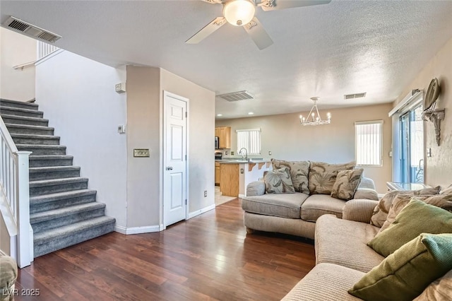 living room featuring dark hardwood / wood-style flooring, ceiling fan with notable chandelier, a textured ceiling, and sink