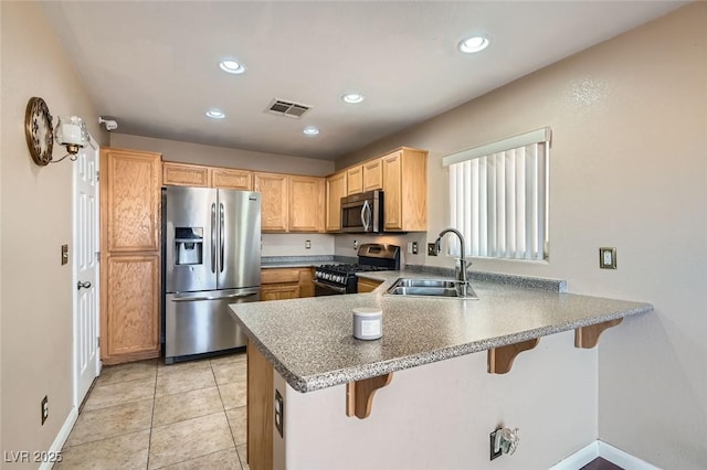 kitchen featuring a kitchen breakfast bar, sink, appliances with stainless steel finishes, light tile patterned flooring, and kitchen peninsula