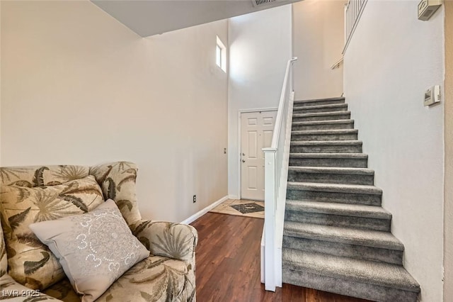 staircase featuring hardwood / wood-style floors and a towering ceiling