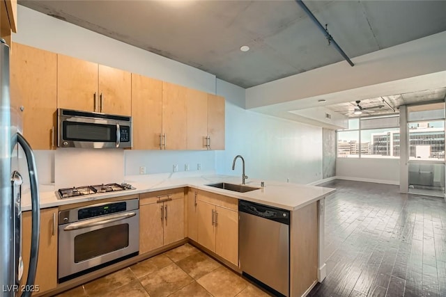 kitchen with ceiling fan, kitchen peninsula, light brown cabinetry, and appliances with stainless steel finishes