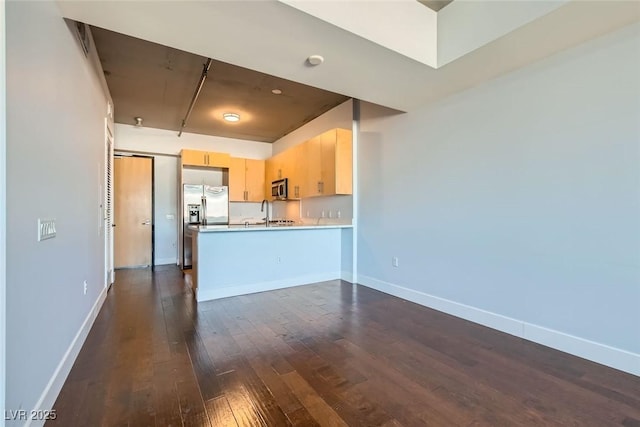 kitchen featuring sink, dark wood-type flooring, kitchen peninsula, light brown cabinetry, and appliances with stainless steel finishes