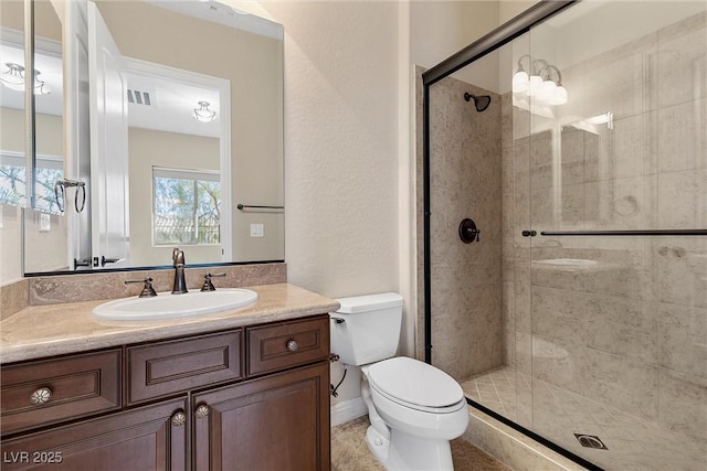 bathroom with toilet, vanity, a shower stall, and visible vents