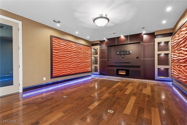 unfurnished living room with a lit fireplace, wood finished floors, and recessed lighting