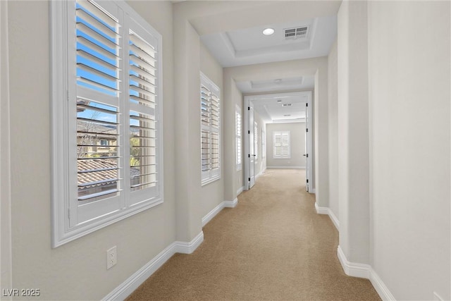 corridor featuring light colored carpet, visible vents, and baseboards