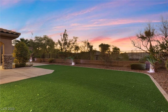 yard at dusk with a fenced backyard and a patio