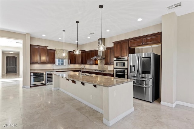 kitchen with light stone counters, stainless steel appliances, a sink, visible vents, and pendant lighting