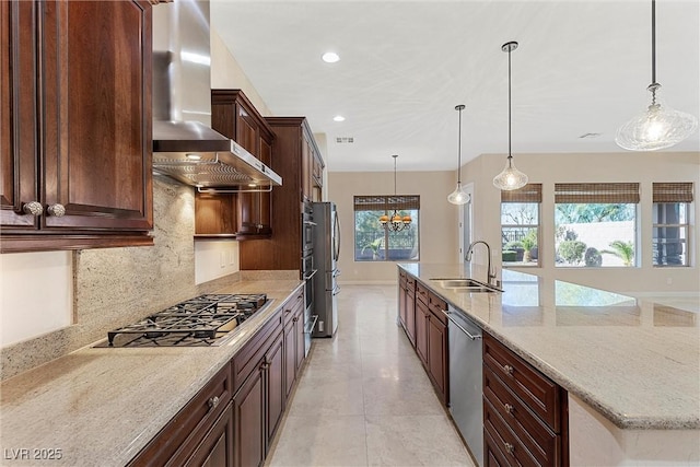 kitchen featuring stainless steel appliances, a sink, visible vents, wall chimney exhaust hood, and tasteful backsplash