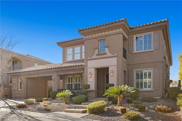 mediterranean / spanish-style home with an attached garage, covered porch, a tiled roof, and stucco siding