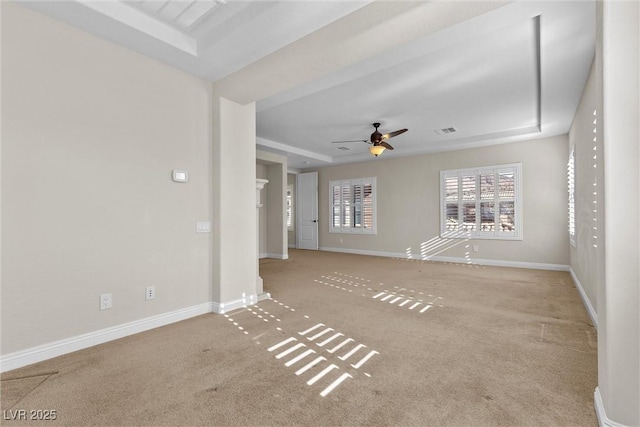 unfurnished living room featuring carpet, a raised ceiling, visible vents, a ceiling fan, and baseboards