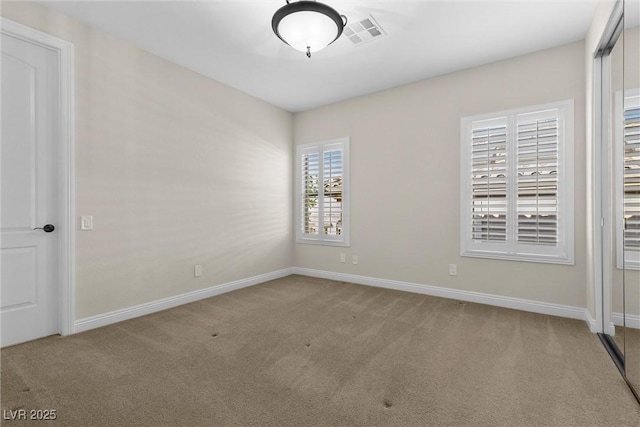 unfurnished room with carpet floors, visible vents, and baseboards