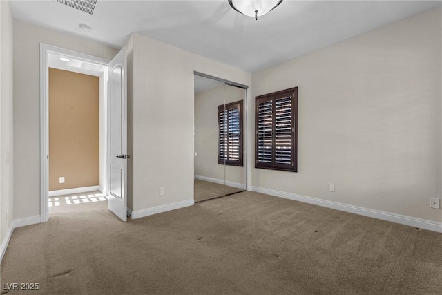 unfurnished bedroom featuring a closet, carpet flooring, visible vents, and baseboards