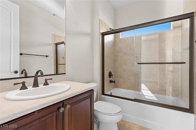 bathroom featuring bath / shower combo with glass door, tile patterned flooring, vanity, and toilet