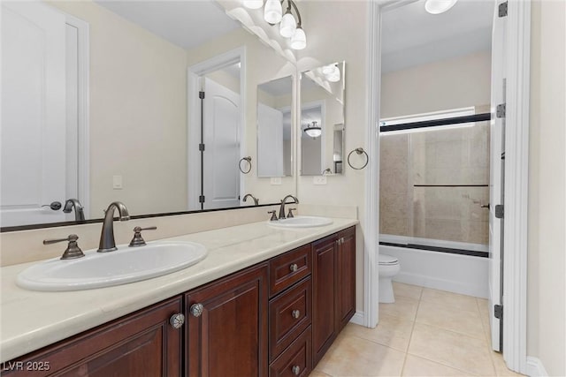 bathroom featuring toilet, double vanity, a sink, and tile patterned floors