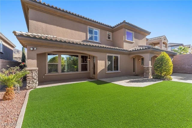 back of property featuring a yard, a tiled roof, and stucco siding