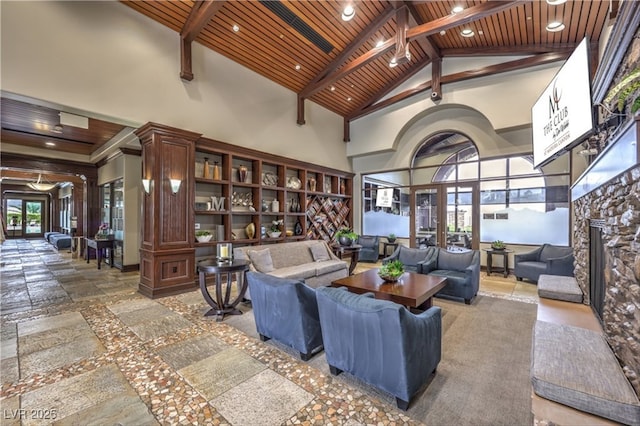 living room featuring beam ceiling, stone tile flooring, wood ceiling, a stone fireplace, and high vaulted ceiling