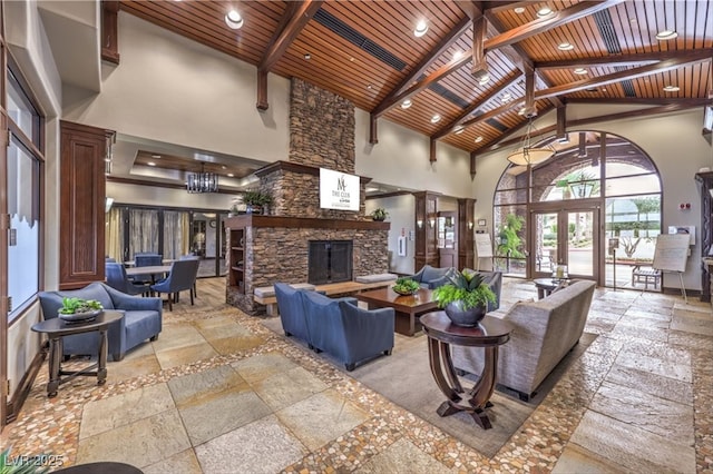 living area with french doors, a stone fireplace, stone tile flooring, and wood ceiling