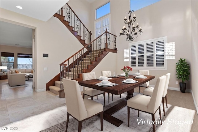 dining area with a chandelier, stairway, a towering ceiling, and baseboards