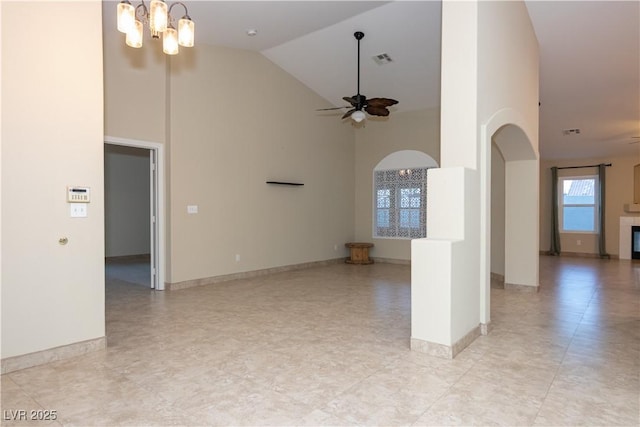 interior space featuring ceiling fan with notable chandelier and a high ceiling