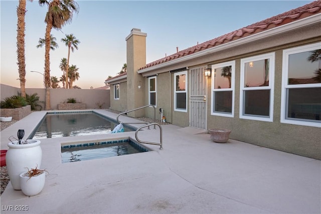 pool at dusk with a patio area and a jacuzzi