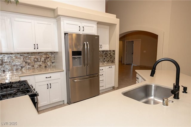 kitchen with sink, white cabinetry, decorative backsplash, stainless steel fridge with ice dispenser, and black gas range oven