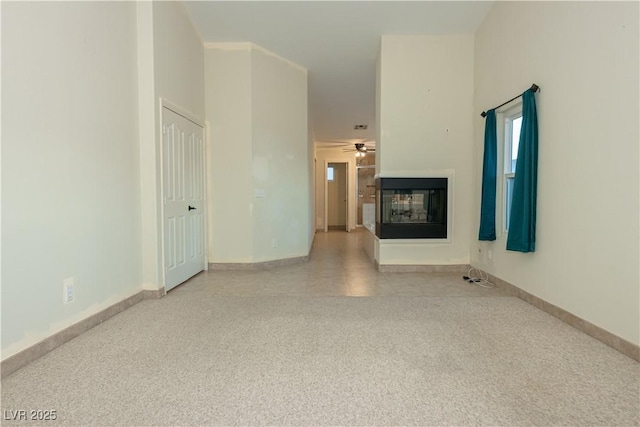 unfurnished room featuring ceiling fan and a multi sided fireplace