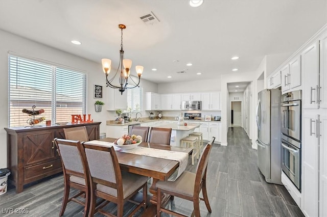 dining room with an inviting chandelier, sink, and dark wood-type flooring