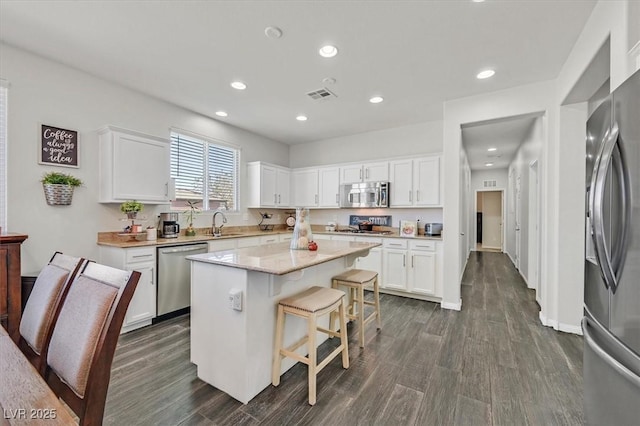 kitchen with stainless steel appliances, a kitchen breakfast bar, a center island, and white cabinets