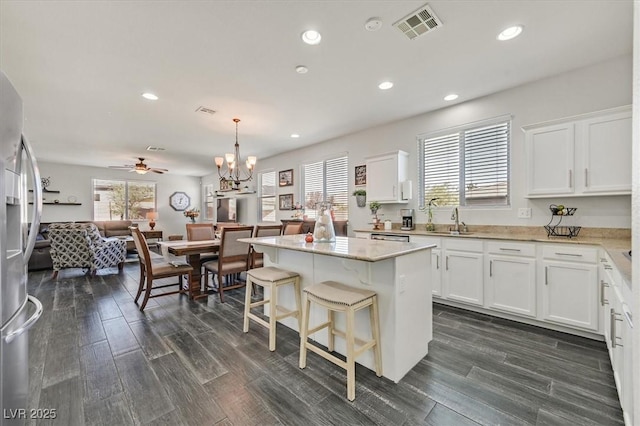 kitchen with hanging light fixtures, sink, a center island, and white cabinets