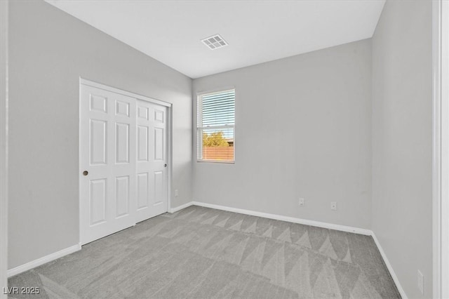 unfurnished bedroom featuring light colored carpet and a closet