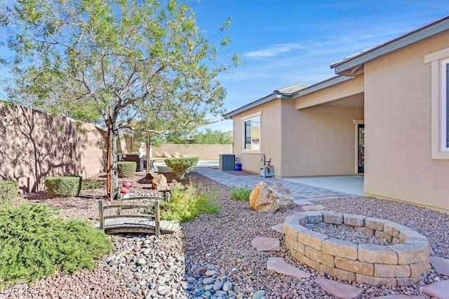 view of yard featuring a patio, central air condition unit, and an outdoor fire pit