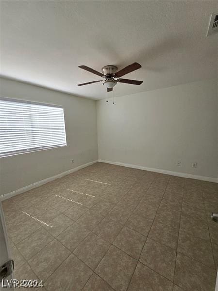 tiled spare room featuring ceiling fan