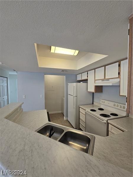 kitchen featuring a raised ceiling, sink, white cabinets, and white appliances