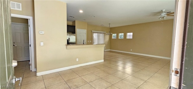 tiled spare room featuring ceiling fan with notable chandelier