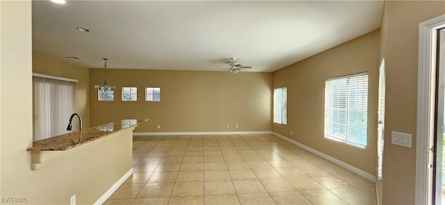 tiled spare room with ceiling fan with notable chandelier and sink