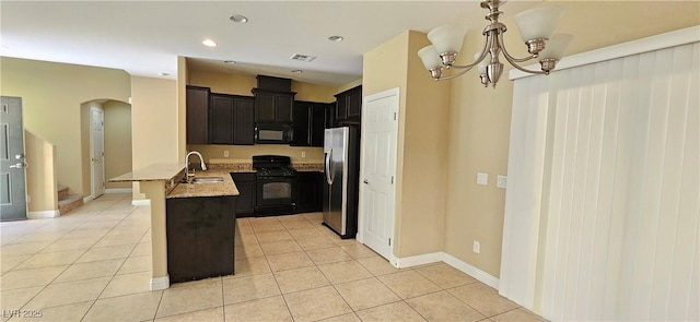 kitchen featuring kitchen peninsula, light stone counters, black appliances, light tile patterned floors, and a notable chandelier