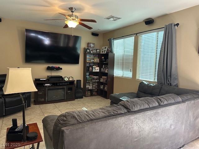 living room featuring a fireplace, ceiling fan, and light tile patterned flooring