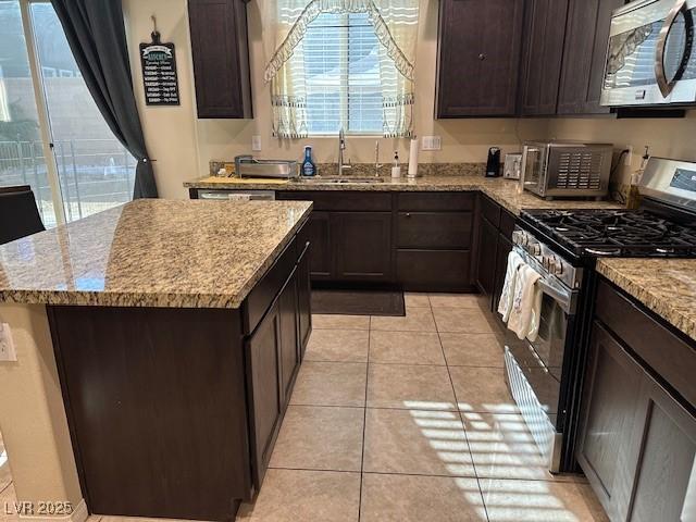 kitchen featuring light tile patterned flooring, sink, a center island, stainless steel appliances, and light stone countertops