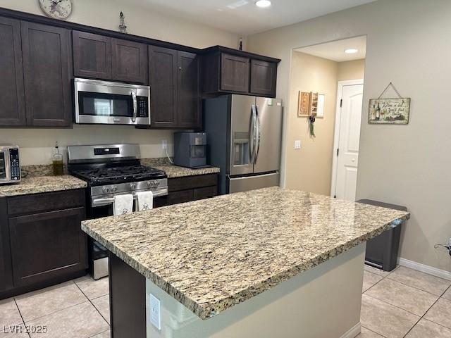 kitchen featuring light stone counters, stainless steel appliances, and a center island