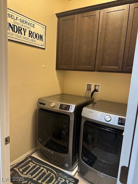 washroom with cabinet space, baseboards, and washer and clothes dryer