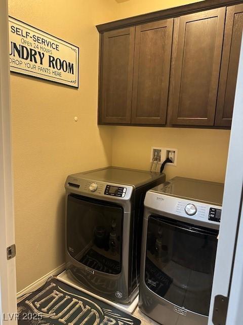 clothes washing area with cabinets and washer and clothes dryer