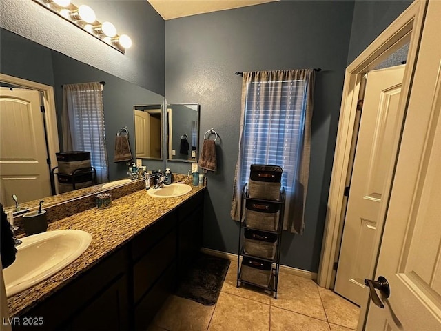 full bath featuring a sink, baseboards, double vanity, and tile patterned floors