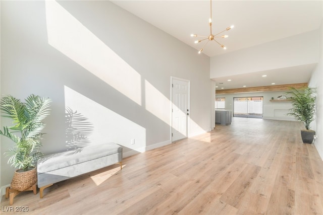 interior space featuring a high ceiling, light hardwood / wood-style flooring, and a notable chandelier