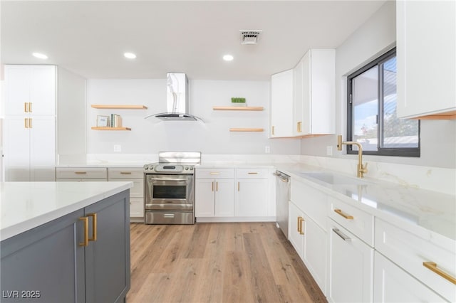 kitchen featuring island exhaust hood, appliances with stainless steel finishes, light stone countertops, sink, and white cabinetry