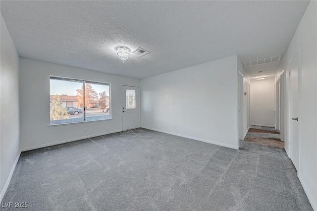 spare room featuring light colored carpet and a textured ceiling