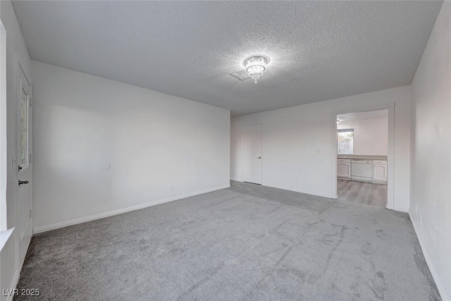 unfurnished room featuring light colored carpet and a textured ceiling